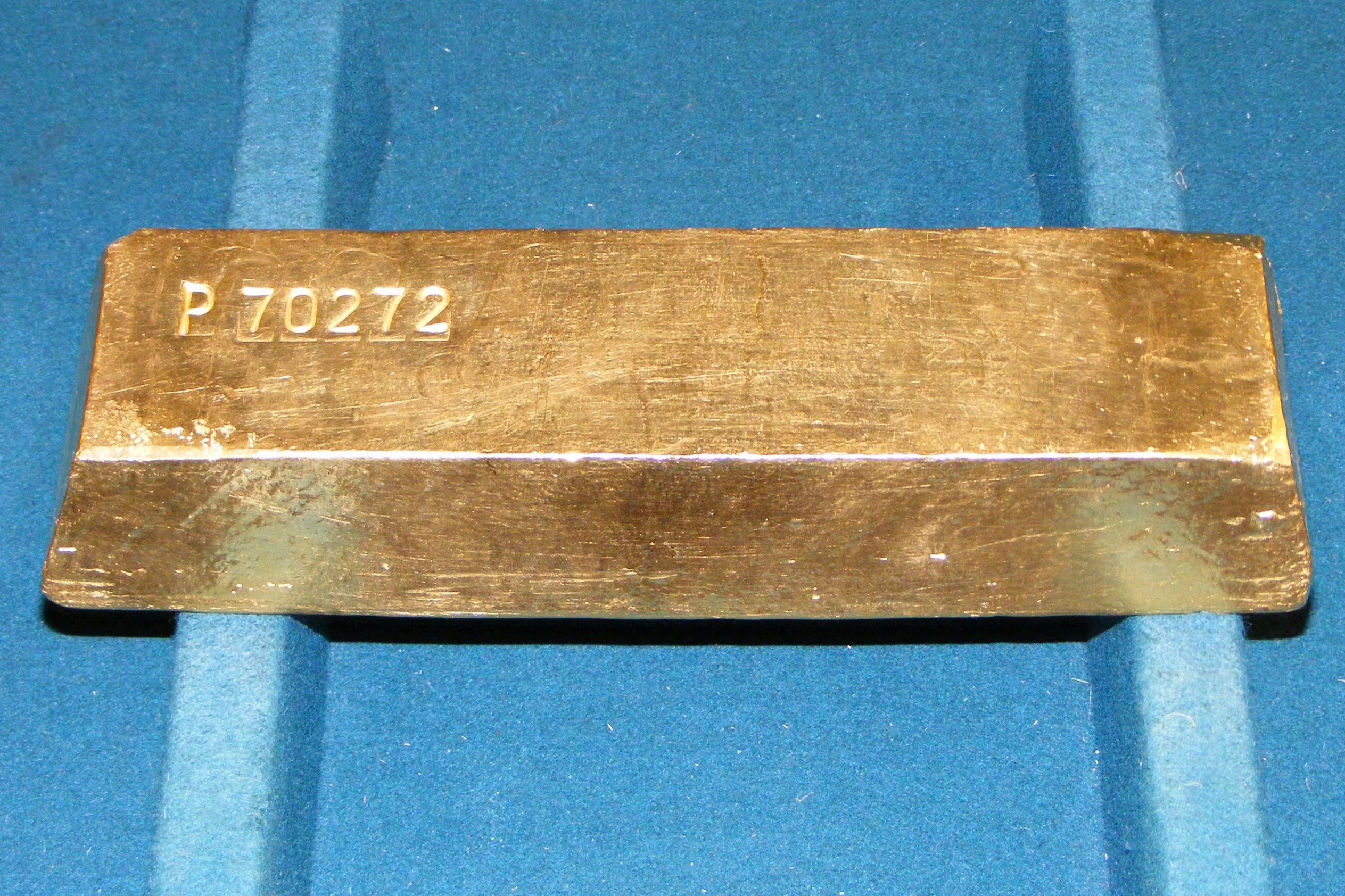 A genuine cast gold bullion bar, showing its serial number and natural surface texture